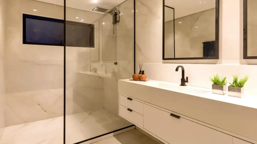 Hero slider image showcasing stylish modern bathroom with beige wall tiles, black framed shower screen, wall-mounted TV and contemporary vanity designed by Dream Bathrooms Glasgow