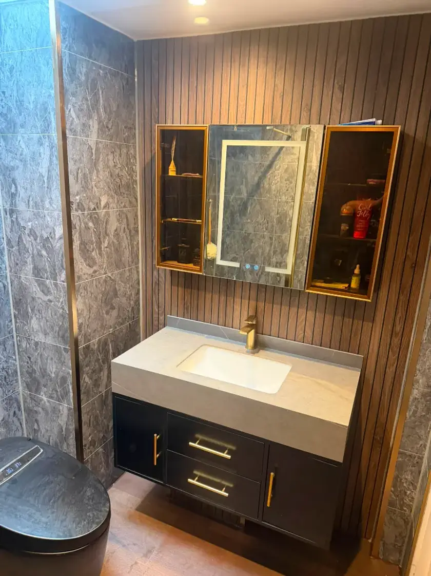 Dark vanity with gold fittings, mirrored cabinet and vertical wood feature wall