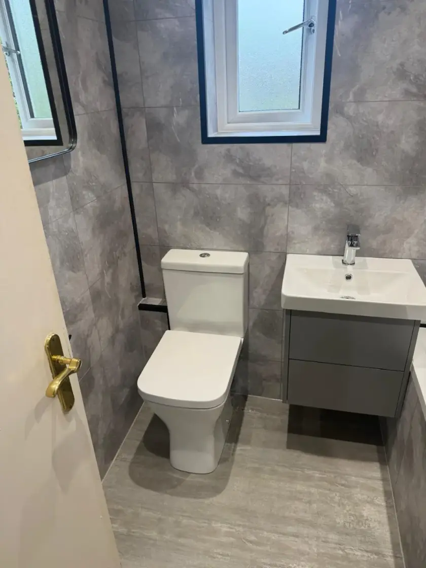 Compact bathroom with grey wall-hung vanity, toilet and large-format wall tiles