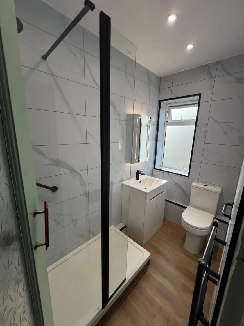 Compact shower room with white wall tiles, grey feature tiles and wood-effect floor