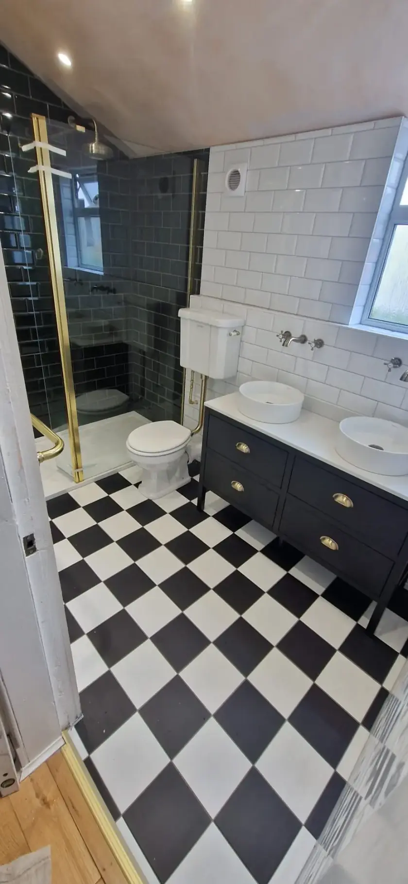 Bathroom with twin countertop basins, black vanity and black-and-white tiled floor