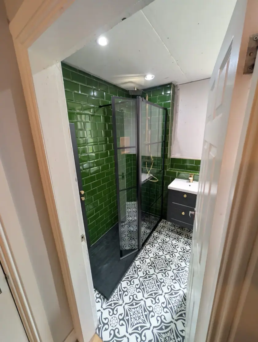 Walk-in shower bathroom with green metro tiles and patterned floor tiles