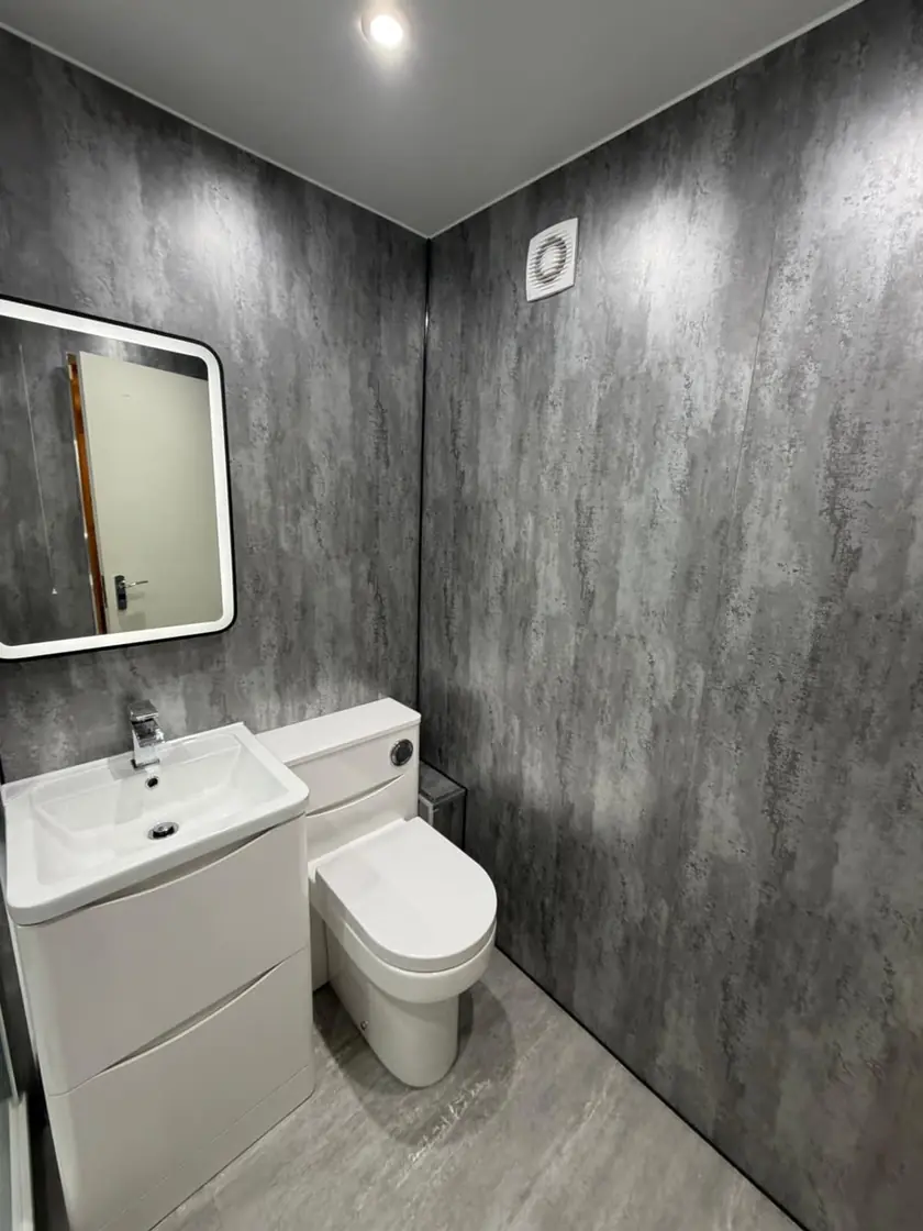 Compact bathroom with grey wet-wall panels, white vanity and close-coupled toilet