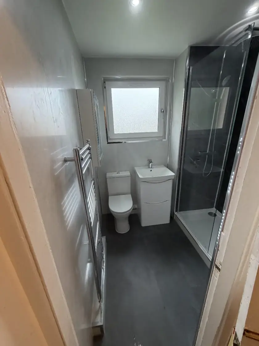 Grey bathroom suite with walk-in shower, white vanity and heated towel rail