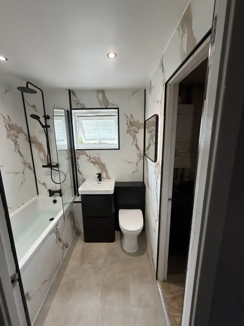 Bathroom with marble-effect bath surround, black shower fittings and black vanity