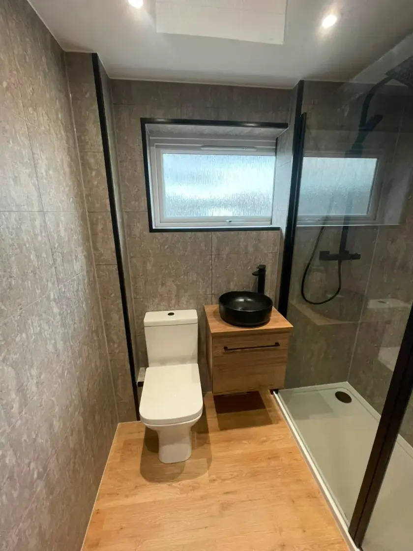 Modern bathroom with walnut vanity, black basin and black-framed walk-in shower