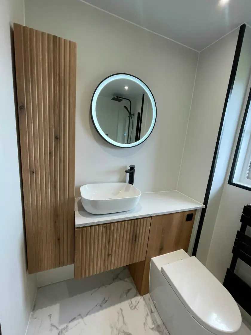Modern wall-hung vanity with wood-slat cabinet, countertop basin and illuminated round mirror