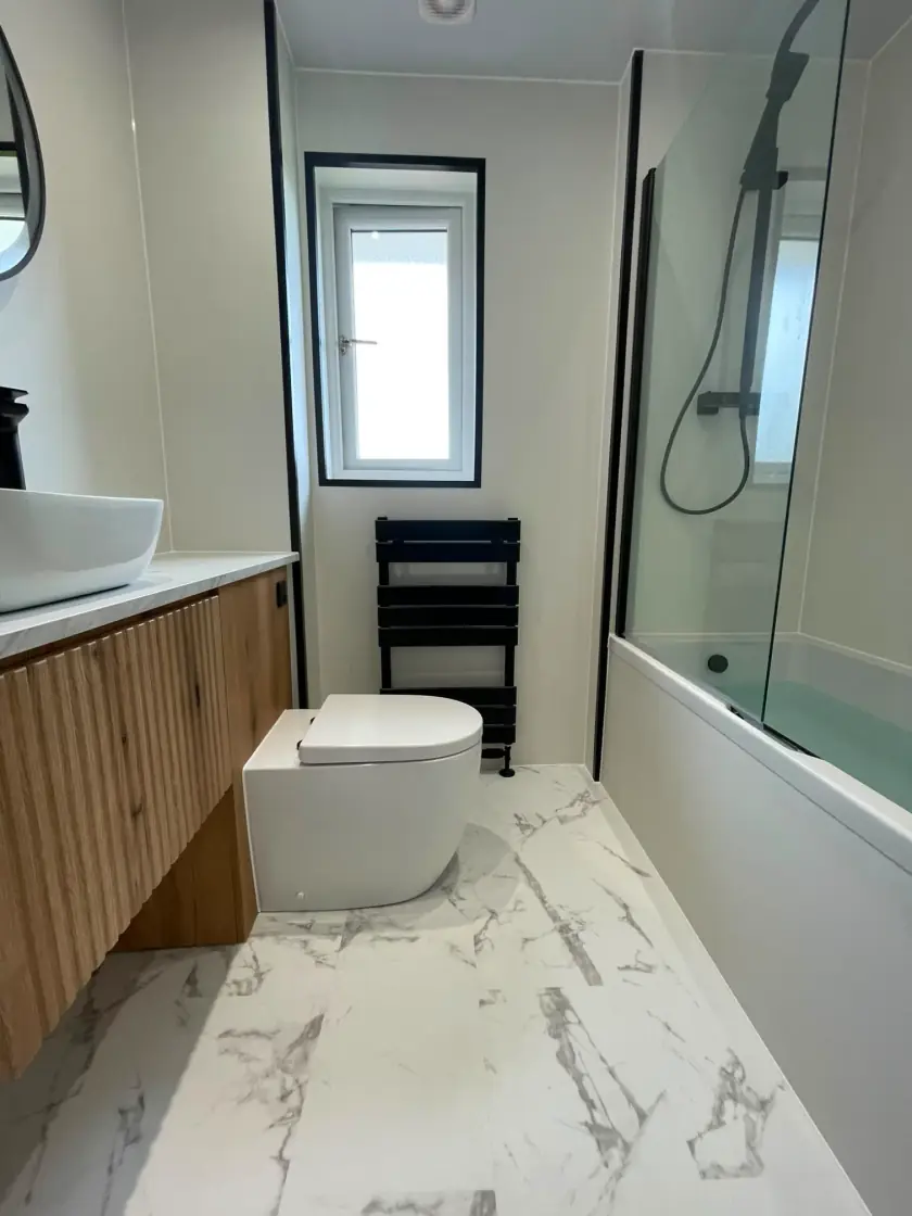 Modern bathroom with long wood vanity, herringbone floor and shower over bath